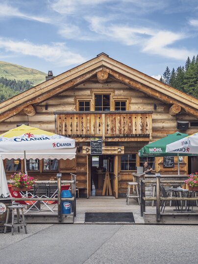 Aussenansicht auf das rustikale Blockhuus mit Sonnenterrasse im Sommer. | © Davos Klosters Mountains