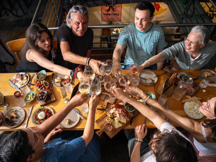 Eight people sit at the table and clink glasses together. | © Davos Klosters Mountains