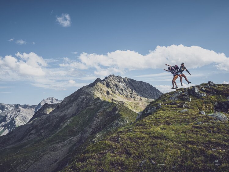 Zwei Wanderer auf Bergpfad springen in die Luft | © Davos Klosters Mountains 